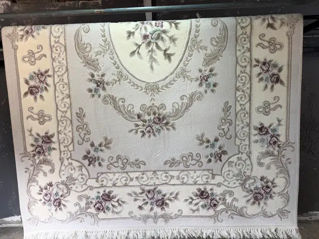 Yıkandıktan sonra tesiste askıya alınmış krem rengi, çiçek desenli halı